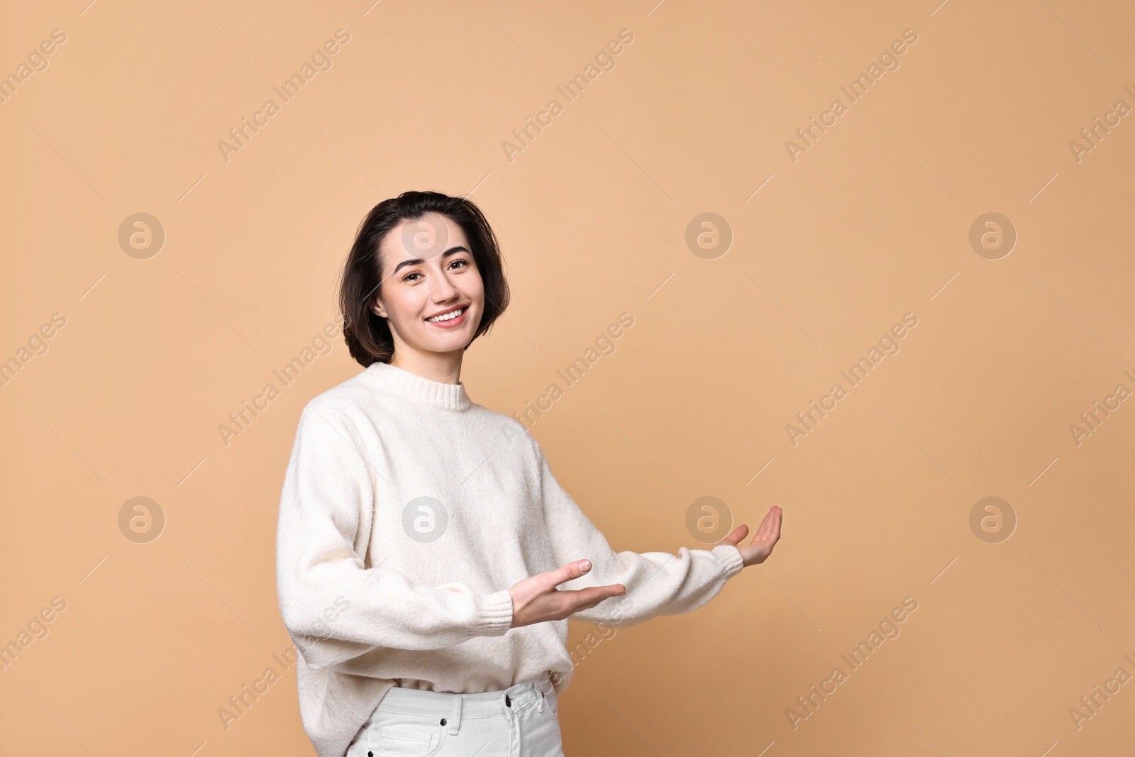 Photo of Cheerful woman welcoming friends or guests on brown background