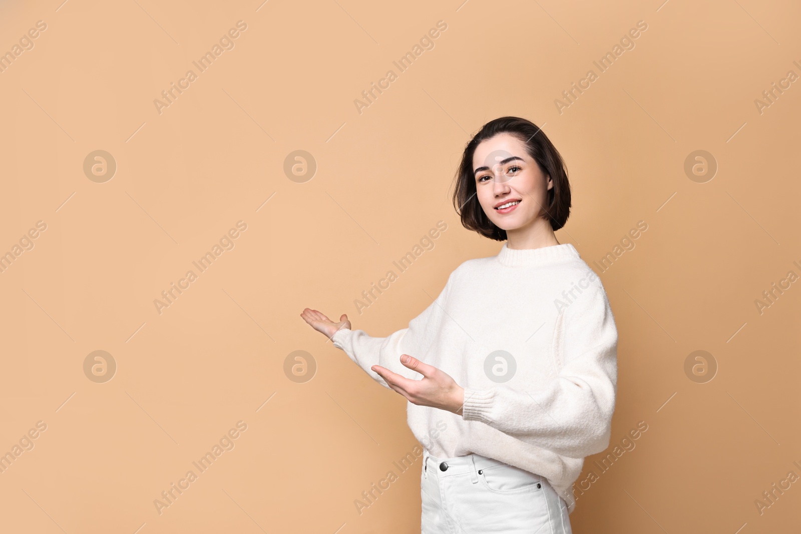 Photo of Cheerful woman welcoming friends or guests on brown background