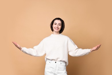 Photo of Cheerful woman welcoming friends or guests on brown background