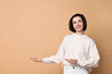 Photo of Cheerful woman welcoming friends or guests on brown background