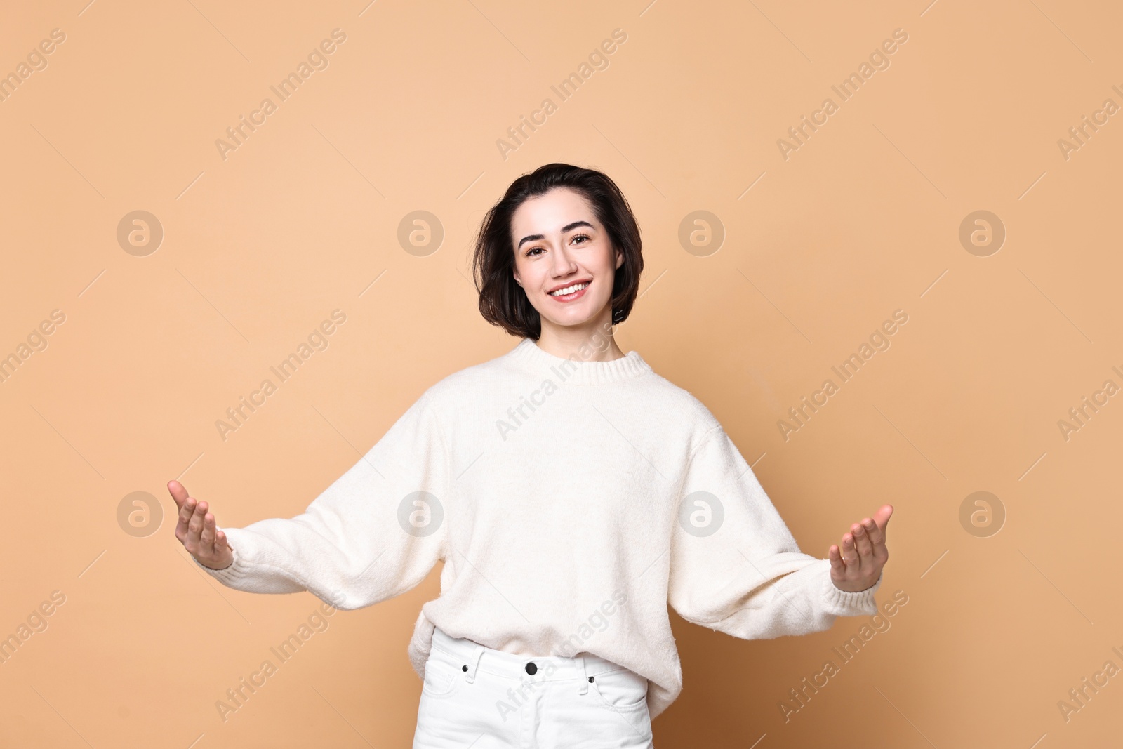 Photo of Cheerful woman welcoming friends or guests on brown background