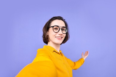 Photo of Happy businesswoman welcoming clients or partners via video call on violet background