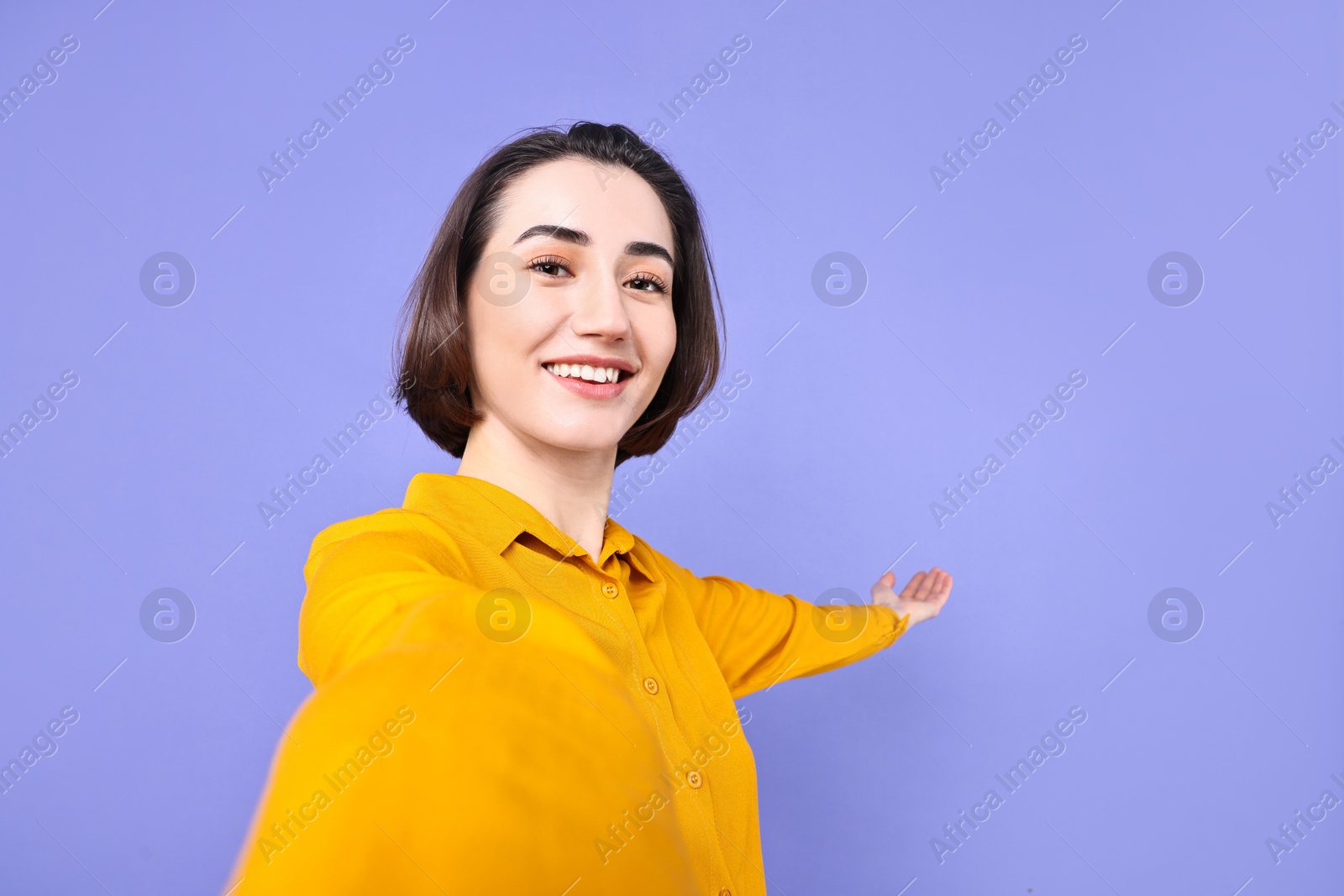 Photo of Happy businesswoman welcoming clients or partners via video call on violet background