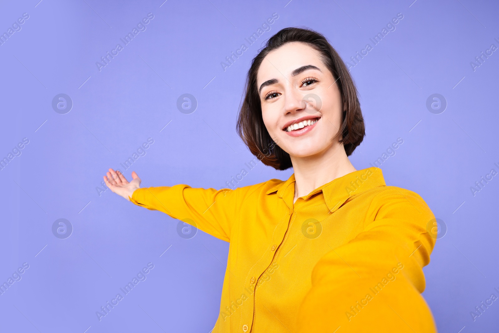 Photo of Happy businesswoman welcoming clients or partners via video call on violet background