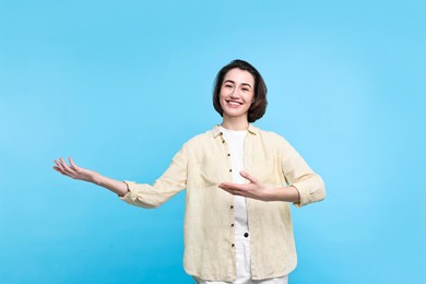 Photo of Cheerful woman welcoming friends or guests on light blue background