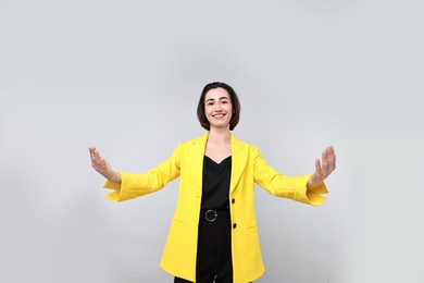 Photo of Happy businesswoman welcoming clients or partners on light grey background