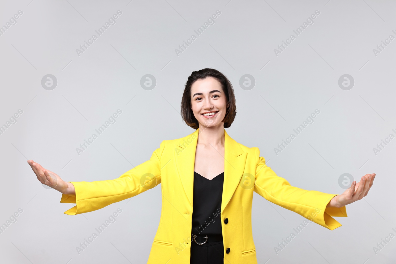 Photo of Happy businesswoman welcoming clients or partners on light grey background