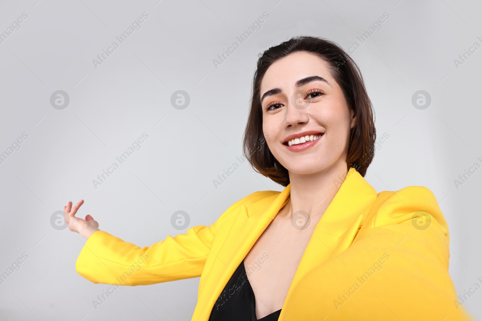 Photo of Happy businesswoman welcoming clients or partners via video call on light grey background