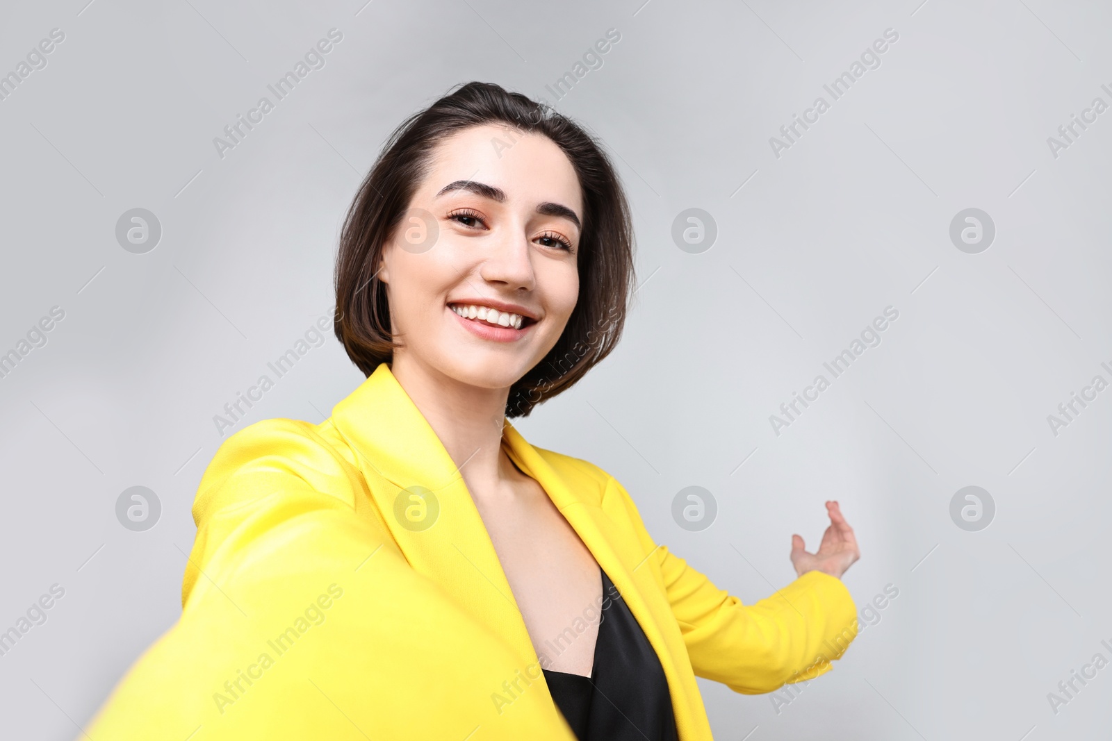 Photo of Happy businesswoman welcoming clients or partners via video call on light grey background