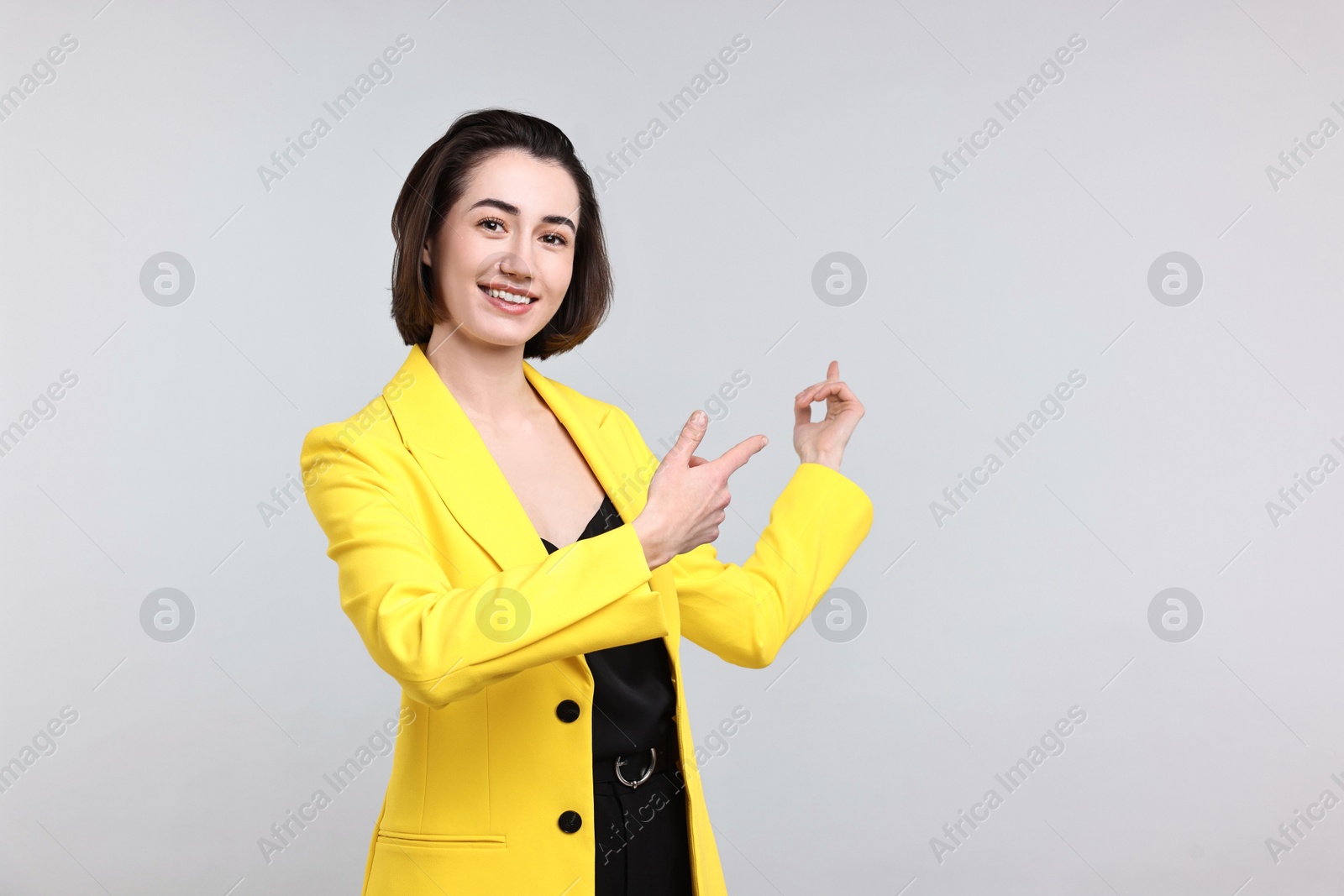 Photo of Happy businesswoman welcoming clients or partners on light grey background