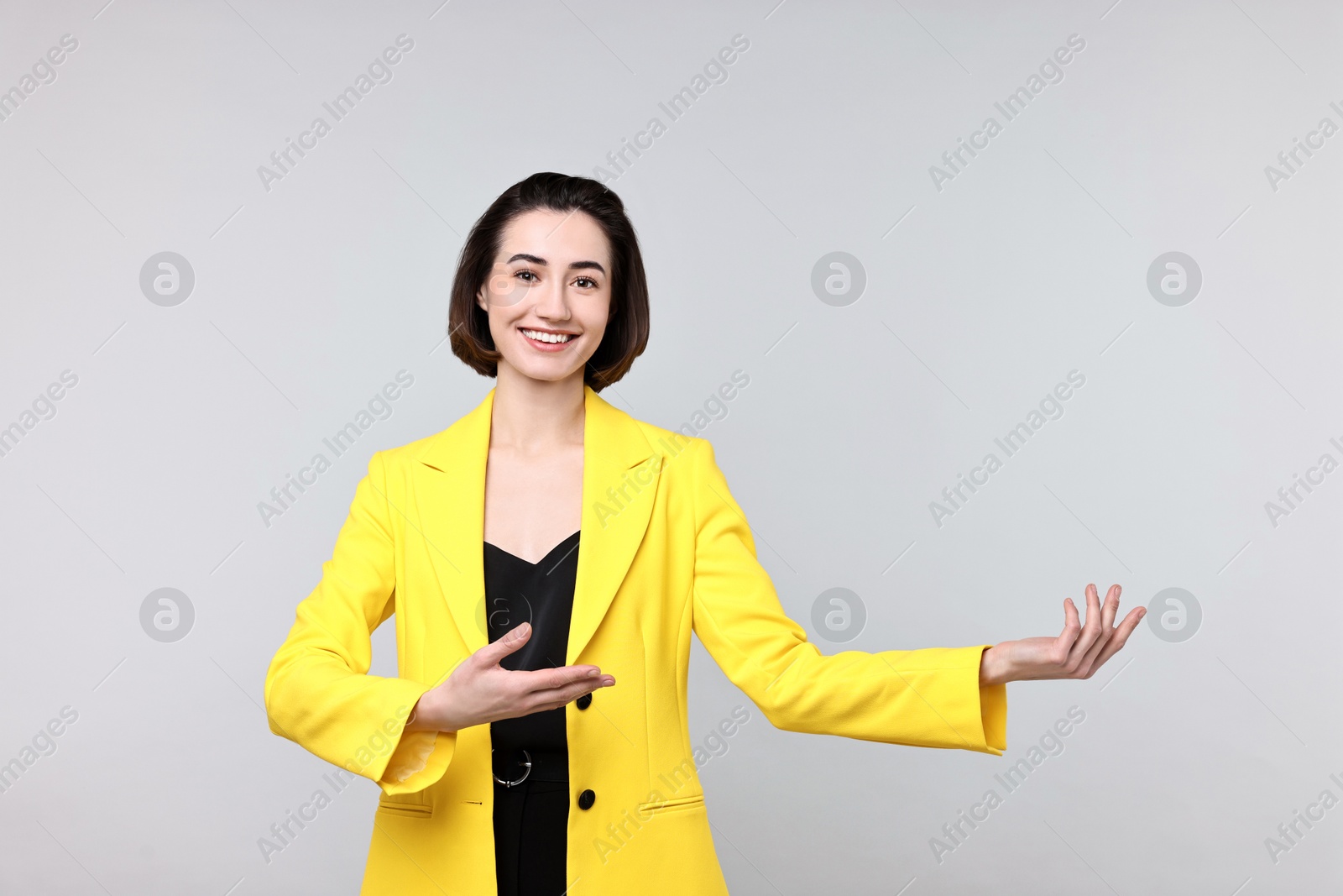 Photo of Happy businesswoman welcoming clients or partners on light grey background