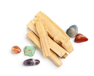 Photo of Palo santo sticks and gemstones isolated on white, top view