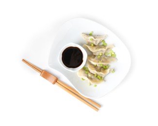 Photo of Tasty gyoza (dumplings), soy sauce and chopsticks isolated on white, top view