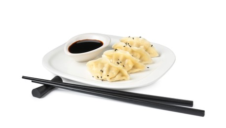 Photo of Tasty gyoza (dumplings), soy sauce and chopsticks isolated on white