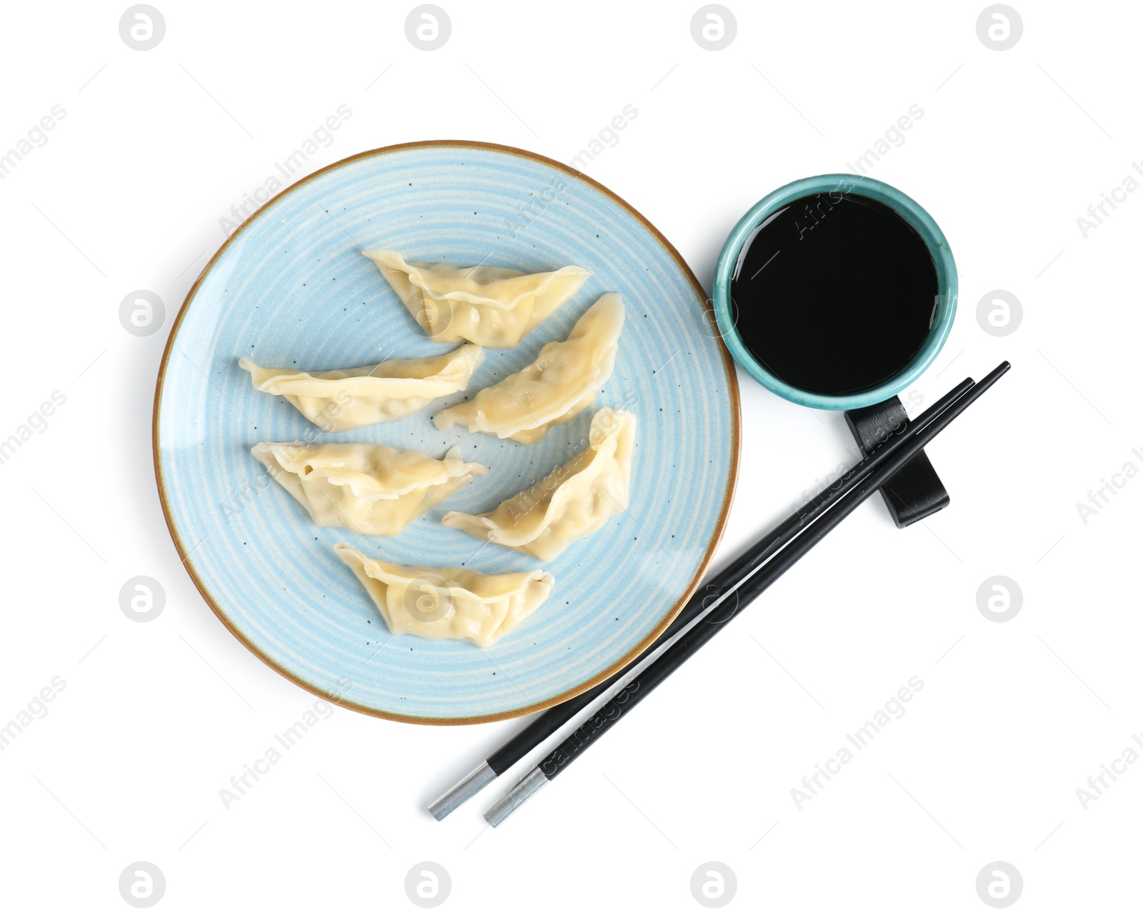 Photo of Tasty gyoza (dumplings), soy sauce and chopsticks isolated on white, top view