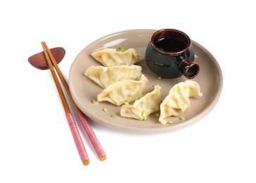 Photo of Tasty gyoza (dumplings), soy sauce and chopsticks isolated on white