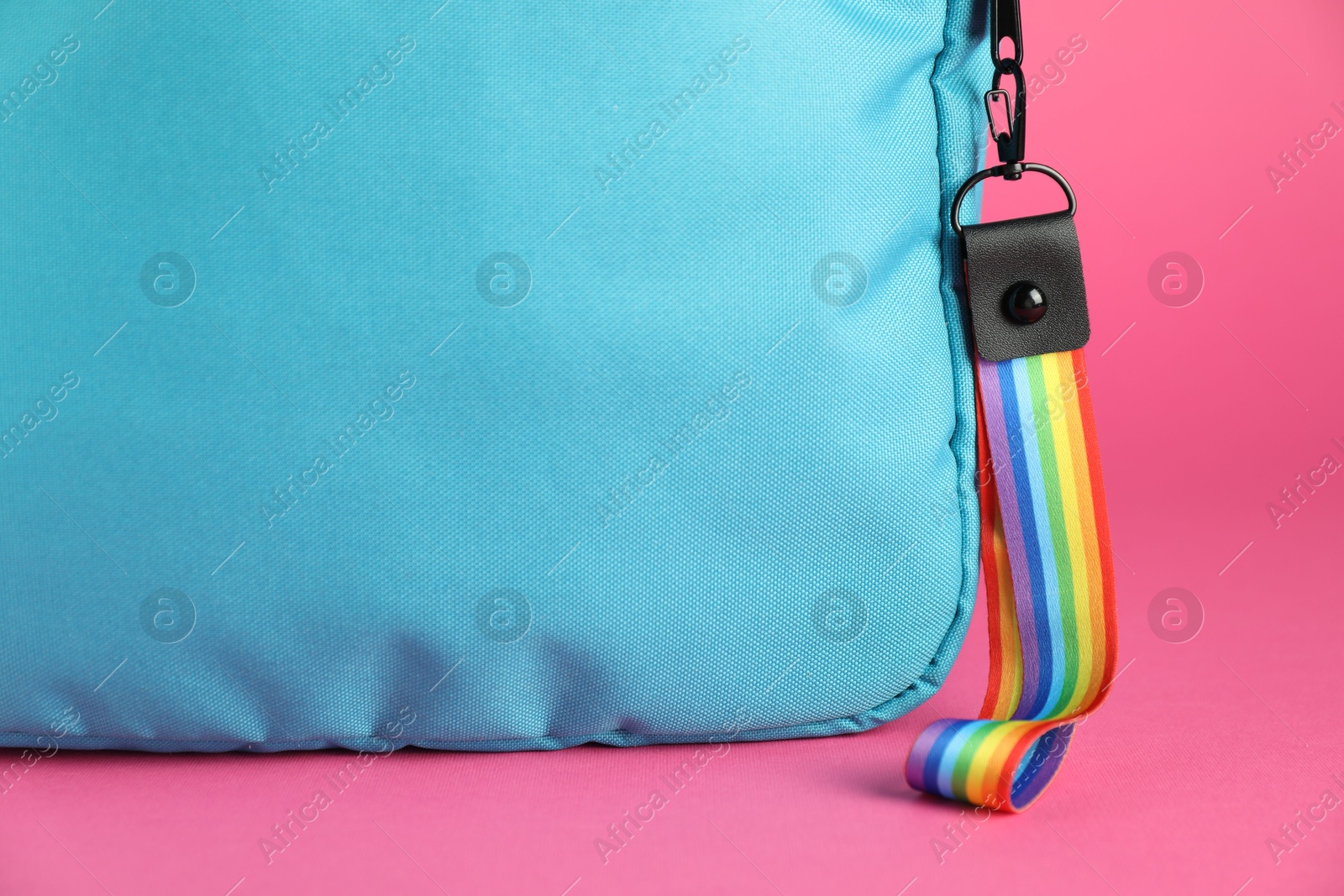 Photo of Backpack with keychain in LGBT colors on pink background, closeup