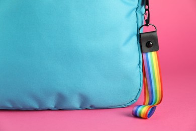 Photo of Backpack with keychain in LGBT colors on pink background, closeup