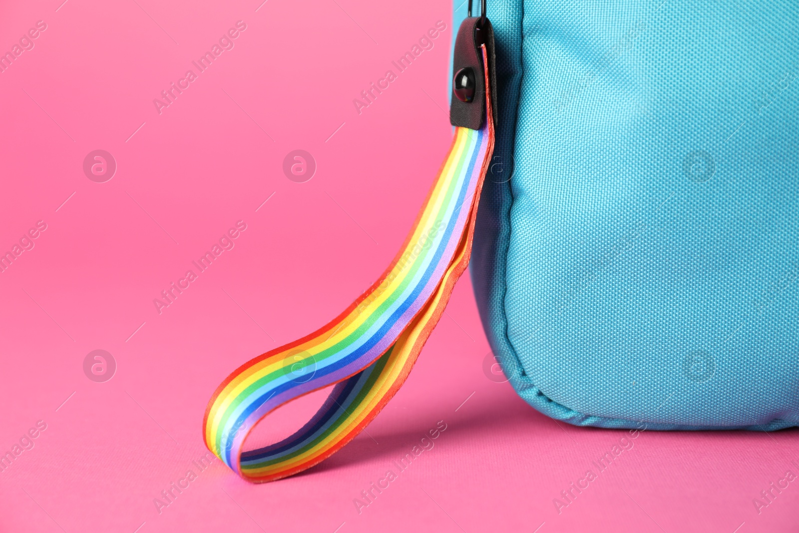 Photo of Backpack with keychain in LGBT colors on pink background, closeup. Space for text