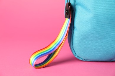 Photo of Backpack with keychain in LGBT colors on pink background, closeup. Space for text