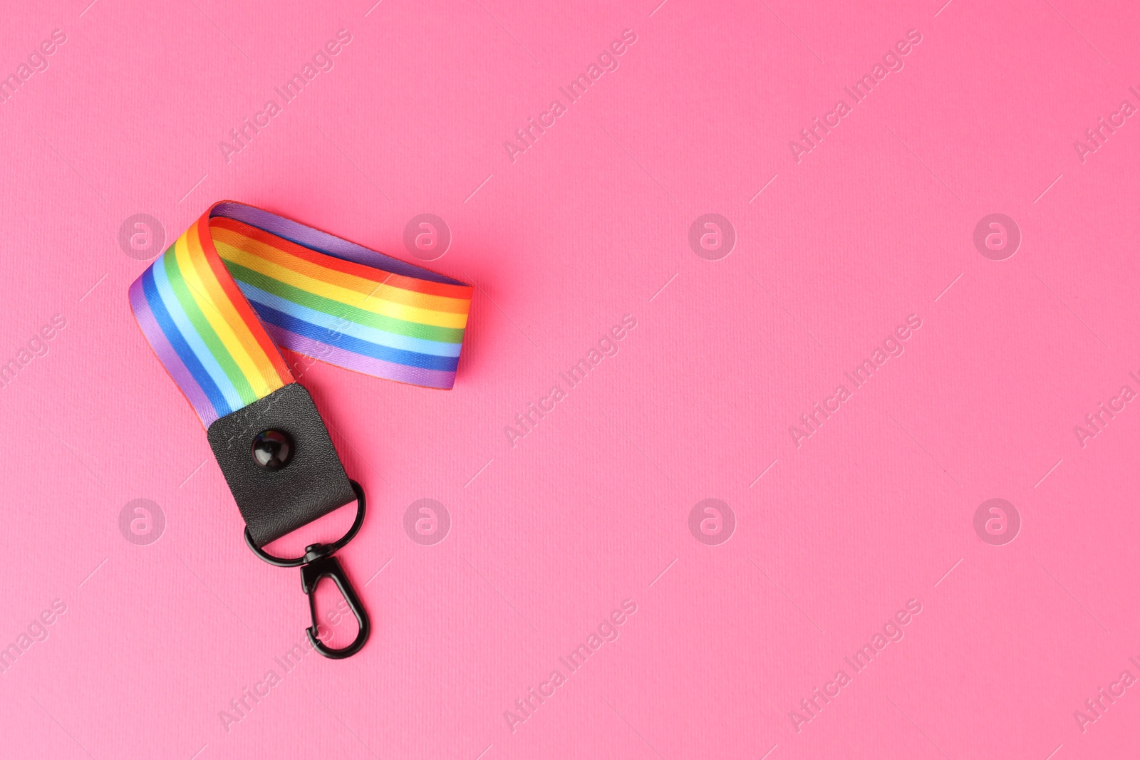 Photo of One keychain in LGBT colors on pink background, top view. Space for text