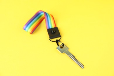 Photo of Key with keychain in LGBT colors on yellow background, closeup