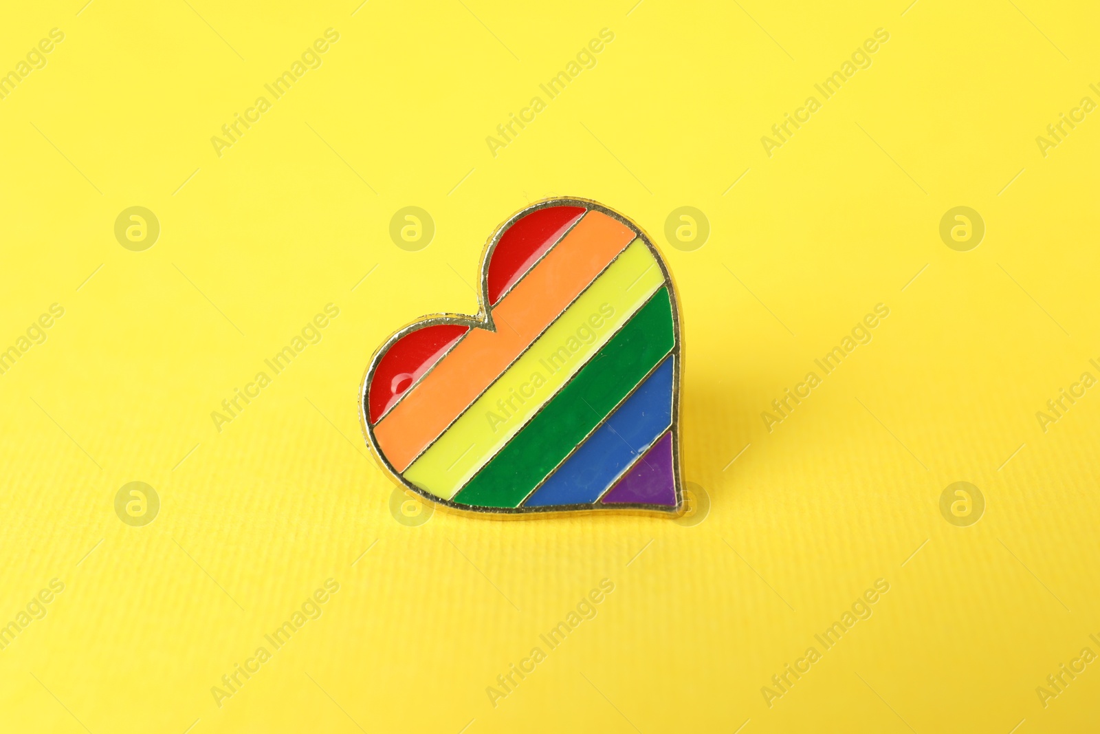 Photo of Heart shaped badge in LGBT colors on yellow background