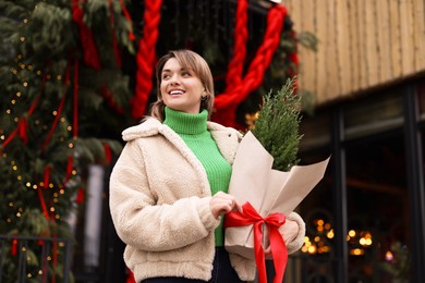 Photo of Happy woman with thuja tree outdoors, low angle view