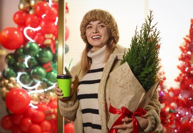 Photo of Happy woman with thuja tree and paper cup at fair