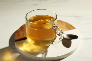 Refreshing green tea in cup on white marble table, closeup