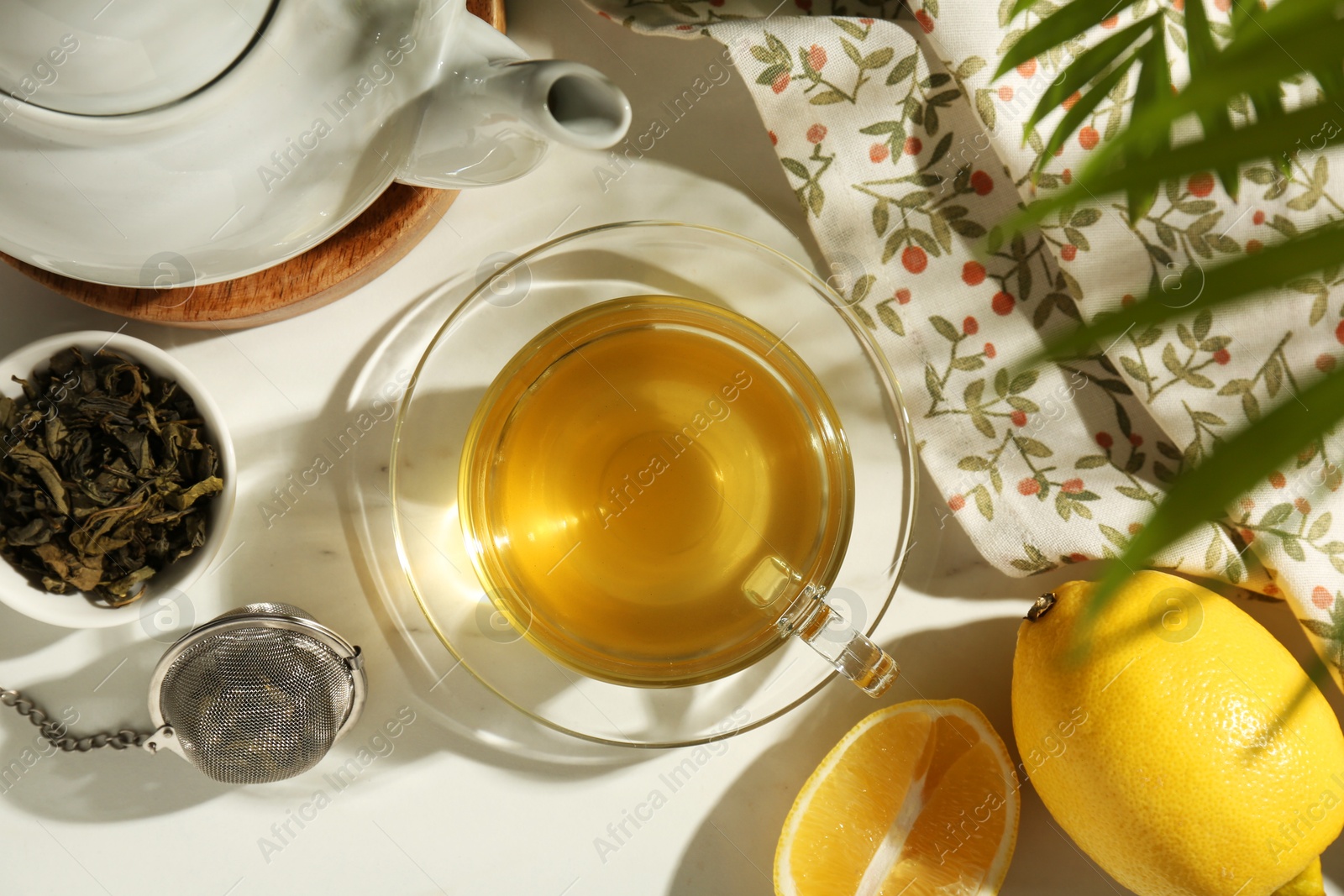 Photo of Flat lay composition with refreshing green tea in cup, dry leaves and cut lemon on white table