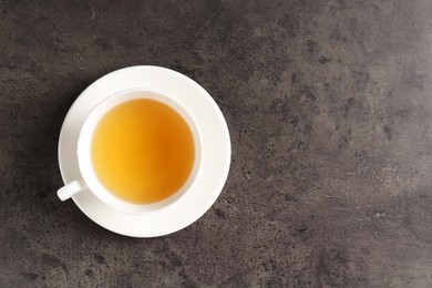 Photo of Refreshing green tea in cup on grey textured table, top view. Space for text