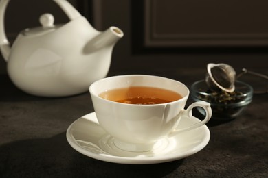 Photo of Refreshing green tea in cup on dark textured table, closeup