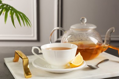 Photo of Refreshing green tea, spoon and slice of lemon on dark textured table