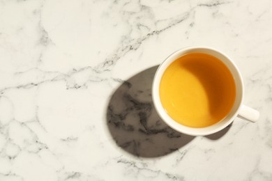 Photo of Refreshing green tea in cup on white marble table, top view. Space for text