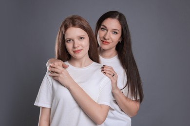 Photo of Portrait of beautiful mother with teenage daughter on grey background