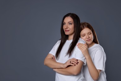 Photo of Family portrait of beautiful mother with teenage daughter on grey background, space for text