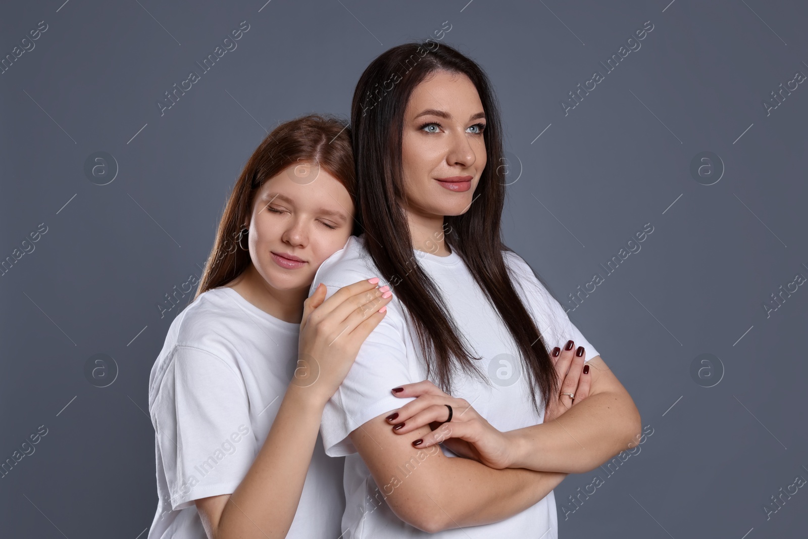 Photo of Portrait of beautiful mother with teenage daughter on grey background