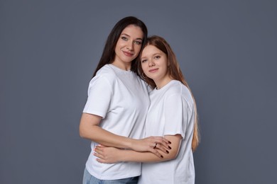 Photo of Portrait of beautiful mother with teenage daughter on grey background