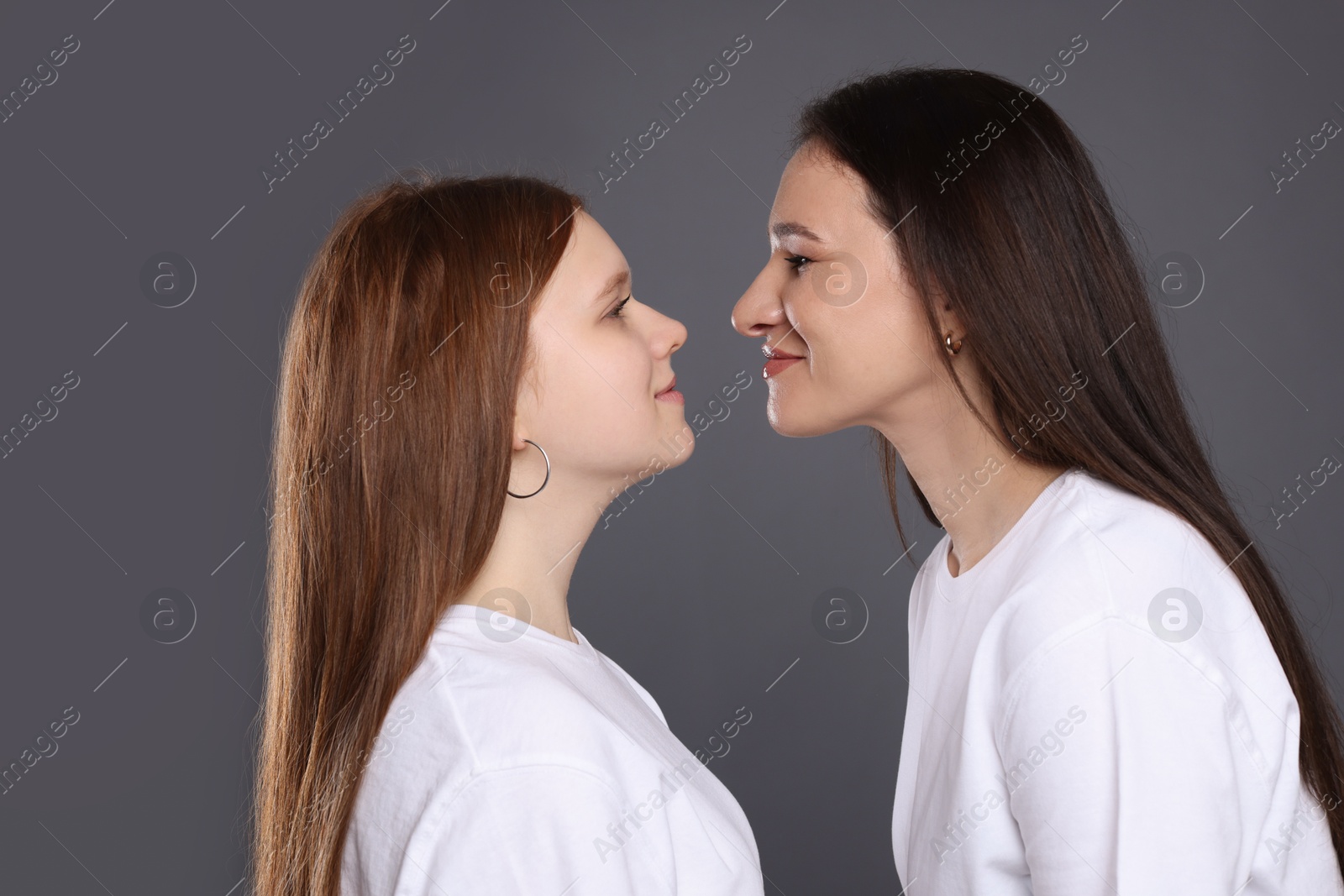 Photo of Portrait of beautiful mother with teenage daughter on grey background