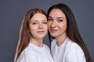 Photo of Portrait of beautiful mother with teenage daughter on grey background