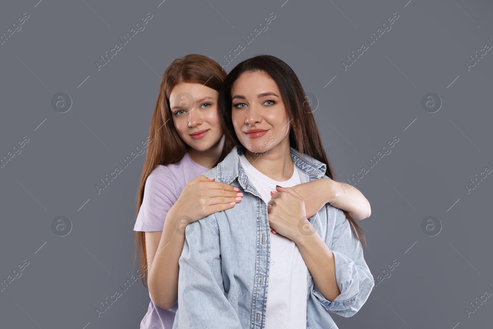 Photo of Portrait of beautiful mother with teenage daughter on grey background