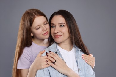 Photo of Portrait of beautiful mother with teenage daughter on grey background