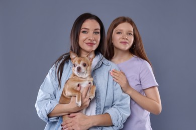 Photo of Family portrait of beautiful mother with teenage daughter and cute Chihuahua dog on grey background