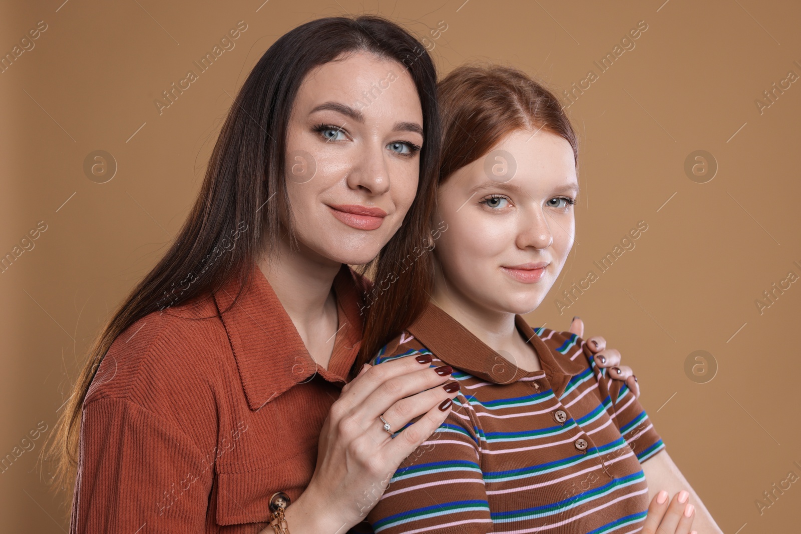 Photo of Portrait of beautiful mother with teenage daughter on dark beige background