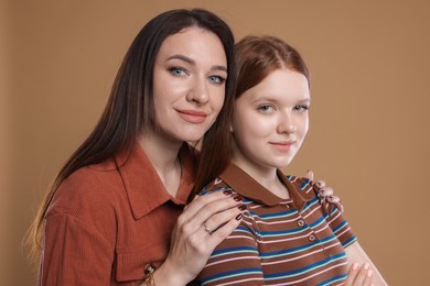 Photo of Portrait of beautiful mother with teenage daughter on dark beige background