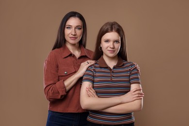 Photo of Portrait of beautiful mother with teenage daughter on dark beige background