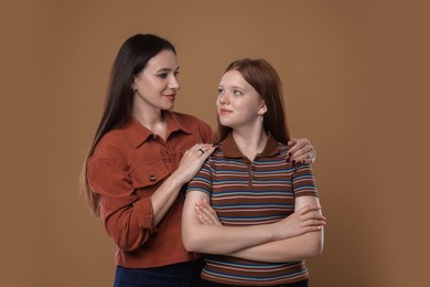 Photo of Portrait of beautiful mother with teenage daughter on dark beige background