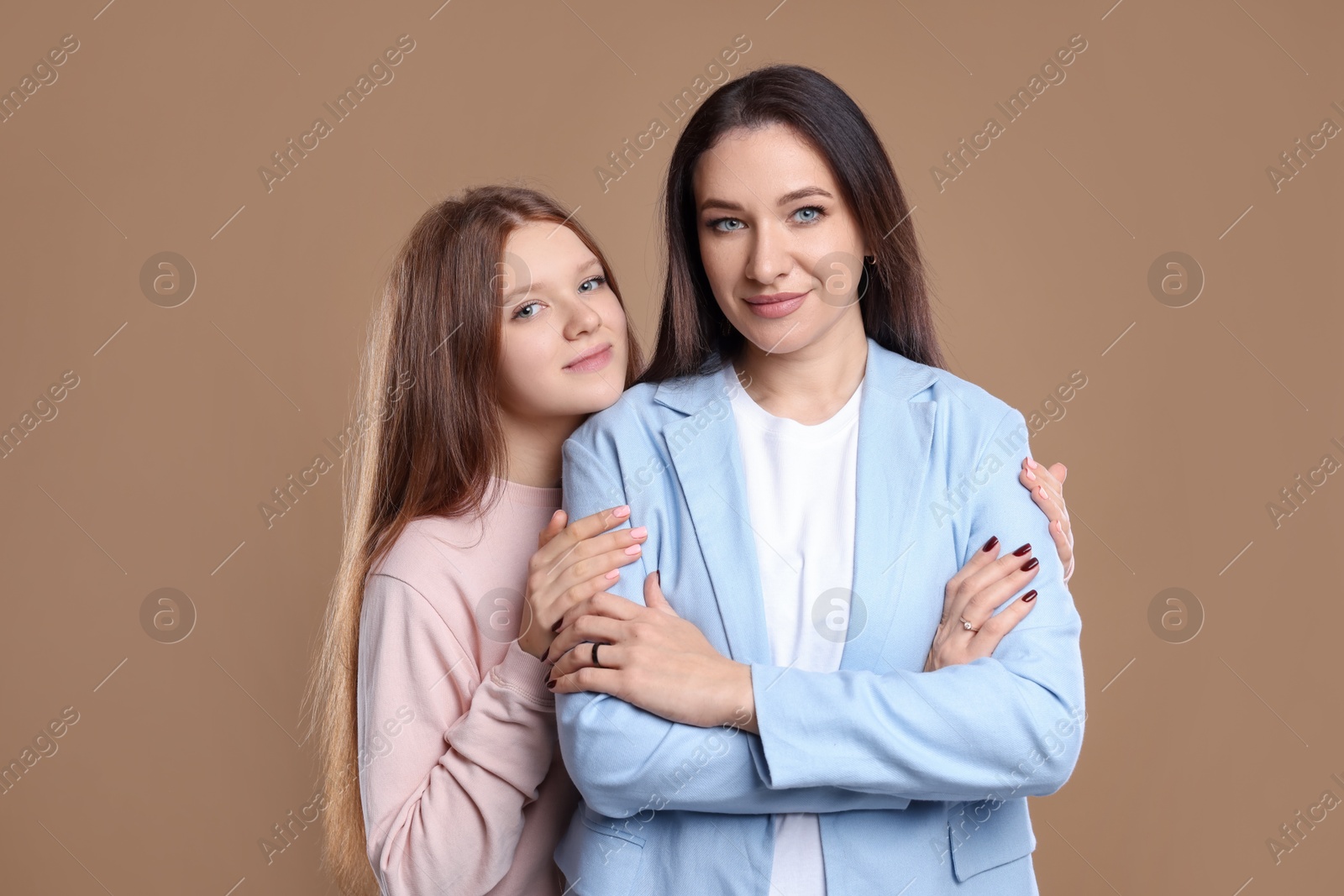 Photo of Portrait of beautiful mother with teenage daughter on dark beige background