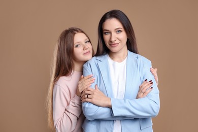 Photo of Portrait of beautiful mother with teenage daughter on dark beige background